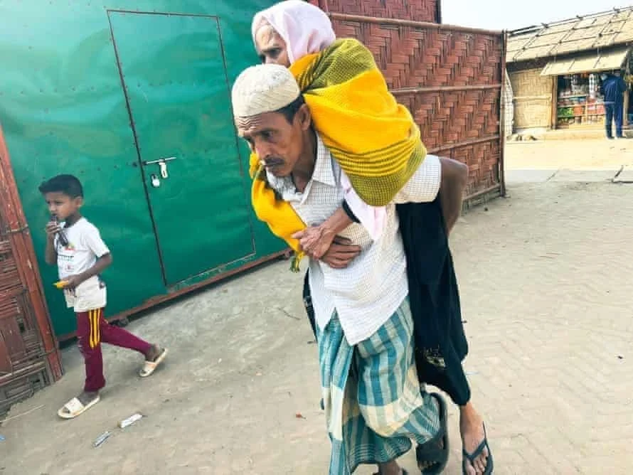 رجل يحمل والدته إلى مرفق للرعاية الصحية في مخيم اللاجئين الروهينجا في كوكس بازار، بنغلاديش.