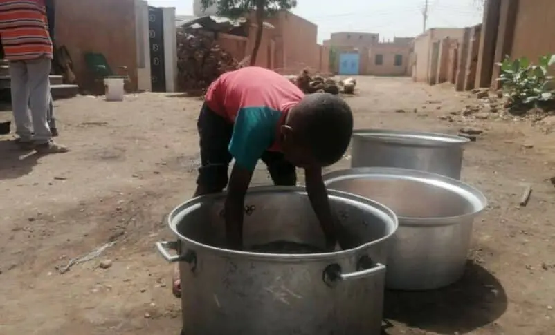 A kid in a Shambat neighbourhood helps in a charity Kitchen group to prepare food for the residents November 10 2023 802x485 1